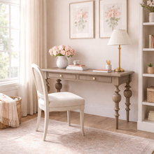Load image into Gallery viewer, Home office view of the Vivienne Desk in Birch finish by Bramble, a mahogany writing desk with sculptural turned legs and two drawers, crafted in Indonesia and offered by Good Bones Furniture to customers across the United States.