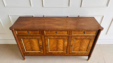 Load image into Gallery viewer, A study in balance and material, the Riley Sideboard draws from European neoclassical design—most notably Louis XVI—reimagined through a quieter, more modern lens. The form is clean and architectural, defined by symmetry, framed panels, and gently tapered legs that give the piece a sense of structure without excess. Cerejeira veneers are carefully bookmatched across each door, revealing a striking cathedral grain that brings movement and depth to the façade. Good Bones Furniture