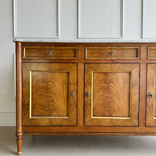 Load image into Gallery viewer, A study in balance and material, the Riley Sideboard draws from European neoclassical design—most notably Louis XVI—reimagined through a quieter, more modern lens. The form is clean and architectural, defined by symmetry, framed panels, and gently tapered legs that give the piece a sense of structure without excess. Cerejeira veneers are carefully bookmatched across each door, revealing a striking cathedral grain that brings movement and depth to the façade. Good Bones Furniture