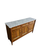 Load image into Gallery viewer, A study in balance and material, the Riley Sideboard draws from European neoclassical design—most notably Louis XVI—reimagined through a quieter, more modern lens. The form is clean and architectural, defined by symmetry, framed panels, and gently tapered legs that give the piece a sense of structure without excess. Cerejeira veneers are carefully bookmatched across each door, revealing a striking cathedral grain that brings movement and depth to the façade. Good Bones Furniture