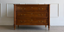 Load image into Gallery viewer, Gently used Ciborium chest by Sarreid showcases timeless European-inspired styling and exceptional craftsmanship. Constructed of solid walnut with a warm fruitwood finish, the piece features fluted corner columns, tapered turned legs, and three generously sized drawers accented with classic brass pulls and decorative faux keyhole escutcheons. Good Bones Furniture