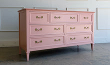 Load image into Gallery viewer, This vintage 7 drawer dresser by Drexel Furniture has been freshly lacquered in Benjamin Moore Mellow Coral, a warm blush-pink finish that gives the piece a soft, elevated look without losing its classic character. The clean rectangular case, framed drawer fronts, tapered legs, and original polished brass hardware create a tailored silhouette with subtle traditional detail. Good Bones Furniture