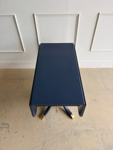 Load image into Gallery viewer, This Federal-inspired vintage drop-leaf table combines elegant classical details with space-saving versatility. Professionally lacquered in Benjamin Moore In the Navy, it features two rounded drop leaves, a single storage drawer with a decorative key and tassel, and a sculptural pedestal base finished with brass-capped feet. Good Bones Furniture