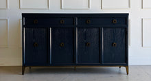 Load image into Gallery viewer, This like-new Hekman sideboard has been professionally refinished in a custom dark Sherwin Williams Naval lacquer, creating a rich, sophisticated finish that highlights the cabinet's clean lines and subtle oak grain texture. Antiqued brass hardware and a matching brass base add warmth and contrast, giving the piece a tailored, designer-inspired look. Good Bones Furniture