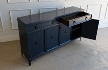 Load image into Gallery viewer, This like-new Hekman sideboard has been professionally refinished in a custom dark Sherwin Williams Naval lacquer, creating a rich, sophisticated finish that highlights the cabinet's clean lines and subtle oak grain texture. Antiqued brass hardware and a matching brass base add warmth and contrast, giving the piece a tailored, designer-inspired look. Good Bones Furniture