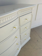 Load image into Gallery viewer, Beige dresser with decorative carvings and gold and clear drawer handles.
