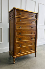 Load image into Gallery viewer, This stately Louis XVI–style chest combines generous storage with a tall, space-conscious silhouette. Crafted from mahogany solids with richly figured cerejeira veneers, it features seven spacious drawers framed by hand-applied gold accents. Fluted corner columns, paneled sides, decorative metal knobs, and tapered legs. Good Bones Furniture