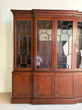 Load image into Gallery viewer, This Georgian-style breakfront china cabinet by Maitland Smith showcases the impeccable construction and richly figured mahogany the maker is known for. The upper cabinet features an illuminated interior behind glass-paneled doors, with adjustable glass shelves that beautifully display china, books, or collected objects. The top is made in three separate sections for easier transport and installation. Good Bones Furniture