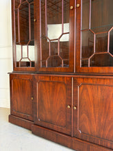 Load image into Gallery viewer, This Georgian-style breakfront china cabinet by Maitland Smith showcases the impeccable construction and richly figured mahogany the maker is known for. The upper cabinet features an illuminated interior behind glass-paneled doors, with adjustable glass shelves that beautifully display china, books, or collected objects. The top is made in three separate sections for easier transport and installation. Good Bones Furniture