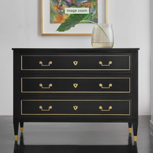 Load image into Gallery viewer, Introduce a touch of European-inspired elegance to your home with the Modern History French 3 Drawer Commode. Its gracefully contoured silhouette and gently tapered legs pay homage to classic French design, while the dramatic ebony-painted case sets a sophisticated tone. Rich in character, the commode’s antique brass accents and hardware provide a refined contrast, lending warmth and timeless appeal.
