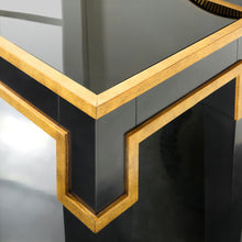 Load image into Gallery viewer, The Modern History Sparro Console blends strong architectural lines with refined materials. Its sleek silhouette is finished in deep ebony paint and highlighted with gold leaf striping that frames the piece with subtle geometric detail. The contrast between the dark finish and warm gold accents creates a sophisticated, gallery-like presence. Good Bones Furniture