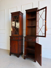 Load image into Gallery viewer, This elegant pair of mahogany display cabinets offers timeless English-inspired styling and exceptional versatility. Rich mahogany veneers showcase beautiful grain patterns throughout, while the astragal-glazed doors add architectural character and provide the perfect backdrop for displaying books, collectibles, china, or decorative objects. Each cabinet features adjustable upper shelving, a convenient storage drawer, and a lower cabinet with additional concealed storage. Good Bones Furniture