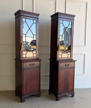 Load image into Gallery viewer, This elegant pair of mahogany display cabinets offers timeless English-inspired styling and exceptional versatility. Rich mahogany veneers showcase beautiful grain patterns throughout, while the astragal-glazed doors add architectural character and provide the perfect backdrop for displaying books, collectibles, china, or decorative objects. Each cabinet features adjustable upper shelving, a convenient storage drawer, and a lower cabinet with additional concealed storage. Good Bones Furniture