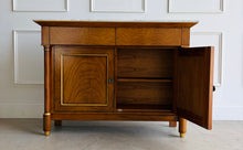 Load image into Gallery viewer, The Philippe Sideboard brings French Empire-inspired elegance and storage to a dining room, entryway, or living space. Crafted with richly figured cerejeira veneer, it features bookmatched door and drawer fronts, fluted columns, and hand-applied gold highlights. A polished white marble top creates a striking contrast with the warm wood tones. Two spacious drawers and a double-door cabinet with an interior shelf provide ample storage for serving pieces, linens, and other essentials. Good Bones Furniture
