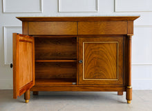 Load image into Gallery viewer, The Philippe Sideboard brings French Empire-inspired elegance and storage to a dining room, entryway, or living space. Crafted with richly figured cerejeira veneer, it features bookmatched door and drawer fronts, fluted columns, and hand-applied gold highlights. A polished white marble top creates a striking contrast with the warm wood tones. Two spacious drawers and a double-door cabinet with an interior shelf provide ample storage for serving pieces, linens, and other essentials. Good Bones Furniture
