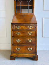 Load image into Gallery viewer, Classic English craftsmanship never goes out of style. This Southampton George III Style Secretary Bookcase is a beautifully proportioned piece that combines elegant display storage, a functional writing desk, and generous drawer storage within a refined, space-saving silhouette. Rich walnut and burl walnut veneers showcase striking natural grain throughout, while the leaded glass door, dentil crown molding, and original Chippendale-style brass hardware add timeless architectural character. Good Bones