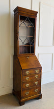 Load image into Gallery viewer, Classic English craftsmanship never goes out of style. This Southampton George III Style Secretary Bookcase is a beautifully proportioned piece that combines elegant display storage, a functional writing desk, and generous drawer storage within a refined, space-saving silhouette. Rich walnut and burl walnut veneers showcase striking natural grain throughout, while the leaded glass door, dentil crown molding, and original Chippendale-style brass hardware add timeless architectural character. Good Bones
