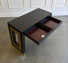 Load image into Gallery viewer, The Ashleigh Console by Theodore Alexander pairs a streamlined silhouette with dramatic decorative details. Professionally lacquered in black, it features substantial rectangular supports accented by textured gold panels, inset antiqued mirror, and brass-capped feet. Two discreet drawers provide concealed storage. Good Bones Furniture
