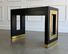 Load image into Gallery viewer, The Ashleigh Console by Theodore Alexander pairs a streamlined silhouette with dramatic decorative details. Professionally lacquered in black, it features substantial rectangular supports accented by textured gold panels, inset antiqued mirror, and brass-capped feet. Two discreet drawers provide concealed storage. Good Bones Furniture