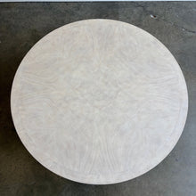 Load image into Gallery viewer, The Lucienne Cocktail Table by Theodore Alexander combines classical ornament with a light, graceful silhouette. Crafted from Khaya wood and richly figured Khaya swirl veneer, its round top rests above a fluted frieze accented with carved leaf motifs. Slender fluted legs connect the upper surface to a wide circular lower shelf. Washed Blanchette finish. Good Bones Furniture