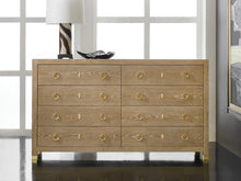 Load image into Gallery viewer, The Ventura Dresser by Modern History offers a refined balance of texture, craftsmanship, and understated luxury. Wrapped in oak random veneer, the surface highlights the natural variation of the wood grain, creating subtle depth and visual movement across the broad drawer fronts. The warm oak tone pairs beautifully with polished solid brass ring pulls and matching escutcheons, lending the piece a timeless, tailored character. Good Bones Furniture