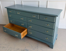 Load image into Gallery viewer, This vintage solid wood 9-drawer dresser has been professionally lacquered in Farrow & Ball Inchyra Blue, a refined blue-green tone that brings depth and understated drama to any room. The clean, traditional lines pair beautifully with new lucite and brass handles, creating a balanced look that feels both classic and freshly updated. Each drawer offers generous storage, making this a functional statement piece for bedrooms, entryways, or living spaces. Good Bones Furniture