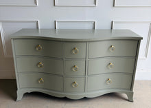 Load image into Gallery viewer, This vintage Table Rock dresser pairs classic construction with a fresh, tailored finish. Lacquered in Sherwin Williams Lauriston Stone, the muted green-gray tone gives the piece a soft, updated presence while still feeling timeless. The gently serpentine front adds movement and elegance, and the new solid brass ring hardware brings a polished contrast to the clean drawer layout. Good Bones Furniture