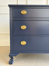 Load image into Gallery viewer, Classic craftsmanship meets a bold designer finish in this vintage ball and claw chest, professionally lacquered in Benjamin Moore In the Navy. The rich navy finish highlights the elegant fluted corner details, carved ball and claw feet, and decorative geometric molding across the upper drawer, while new solid brass Hepplewhite drawer pulls add a timeless finishing touch. Good Bones Furniture