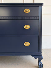 Load image into Gallery viewer, Classic craftsmanship meets a bold designer finish in this vintage ball and claw chest, professionally lacquered in Benjamin Moore In the Navy. The rich navy finish highlights the elegant fluted corner details, carved ball and claw feet, and decorative geometric molding across the upper drawer, while new solid brass Hepplewhite drawer pulls add a timeless finishing touch. Good Bones Furniture
