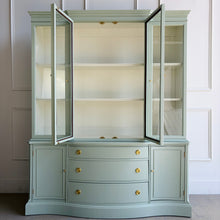 Load image into Gallery viewer, This vintage Bassett China Cabinet has been professionally lacquered in Benjamin Moore Saybrook Sage on the exterior with a creamy white interior for a bright, clean display. The classic silhouette features four glass doors on the upper hutch for showcasing china, glassware, and collections, while the lower cabinet offers a graceful serpentine front with ample closed storage. Warm brass knobs finish the look with an elegant, timeless contrast. Good Bones Furniture