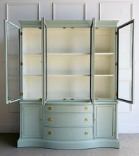Load image into Gallery viewer, This vintage Bassett China Cabinet has been professionally lacquered in Benjamin Moore Saybrook Sage on the exterior with a creamy white interior for a bright, clean display. The classic silhouette features four glass doors on the upper hutch for showcasing china, glassware, and collections, while the lower cabinet offers a graceful serpentine front with ample closed storage. Warm brass knobs finish the look with an elegant, timeless contrast. Good Bones Furniture