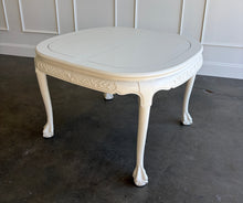 Load image into Gallery viewer, This vintage Chippendale-style dining table combines elaborate traditional detailing with a fresh, versatile finish. Professionally lacquered in Benjamin Moore Swiss Coffee darkened by 50%, it has a warm, creamy white appearance that highlights its carved details without feeling stark. Good Bones Furniture