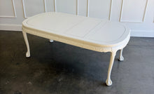 Load image into Gallery viewer, This vintage Chippendale-style dining table combines elaborate traditional detailing with a fresh, versatile finish. Professionally lacquered in Benjamin Moore Swiss Coffee darkened by 50%, it has a warm, creamy white appearance that highlights its carved details without feeling stark. Good Bones Furniture