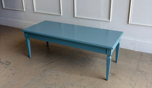 Load image into Gallery viewer, This vintage coffee table pairs classic architectural details with a fresh, colorful finish. Professionally lacquered in Sherwin-Williams Moody Blue, it features a rectangular top, subtly molded apron, carved corner accents, and tapered legs with recessed panel detailing. Good Bones Furniture