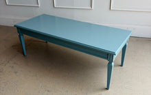 Load image into Gallery viewer, This vintage coffee table pairs classic architectural details with a fresh, colorful finish. Professionally lacquered in Sherwin-Williams Moody Blue, it features a rectangular top, subtly molded apron, carved corner accents, and tapered legs with recessed panel detailing. Good Bones Furniture