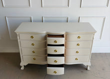 Load image into Gallery viewer, This vintage 12 drawer dresser by Continental Furniture has been professionally lacquered in Benjamin Moore Natural Linen, giving the traditional silhouette a softer, updated presence while highlighting its elegant serpentine front and carved details. Resting on sculpted claw feet with fluted corner accents, new Hepplewhite hardware. Good Bones Furniture