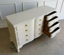Load image into Gallery viewer, This vintage 12 drawer dresser by Continental Furniture has been professionally lacquered in Benjamin Moore Natural Linen, giving the traditional silhouette a softer, updated presence while highlighting its elegant serpentine front and carved details. Resting on sculpted claw feet with fluted corner accents, new Hepplewhite hardware. Good Bones Furniture