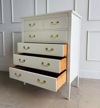 Load image into Gallery viewer, Vintage Dixie chest offers generous storage within a tall, space-conscious silhouette. Professionally lacquered in Benjamin Moore Swiss Coffee at 150% strength, its warm creamy-white finish complements the chest’s clean lines, inset drawer fronts, and tapered legs. Six drawers provide ample storage, while new solid brass drop-bail pulls add a polished contrast. Good Bones Furniture