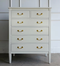 Load image into Gallery viewer, Vintage Dixie chest offers generous storage within a tall, space-conscious silhouette. Professionally lacquered in Benjamin Moore Swiss Coffee at 150% strength, its warm creamy-white finish complements the chest’s clean lines, inset drawer fronts, and tapered legs. Six drawers provide ample storage, while new solid brass drop-bail pulls add a polished contrast. Good Bones Furniture