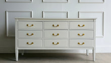 Load image into Gallery viewer, Vintage 9 drawer dresser by Dixie Furniture offers substantial storage within a timeless, beautifully proportioned silhouette. Professionally lacquered in Benjamin Moore Swiss Coffee at 150% strength, its warm creamy-white finish highlights the clean lines, inset drawer fronts, and tapered legs. Good Bones Furniture