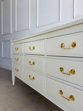 Load image into Gallery viewer, Vintage 9 drawer dresser by Dixie Furniture offers substantial storage within a timeless, beautifully proportioned silhouette. Professionally lacquered in Benjamin Moore Swiss Coffee at 150% strength, its warm creamy-white finish highlights the clean lines, inset drawer fronts, and tapered legs. Good Bones Furniture
