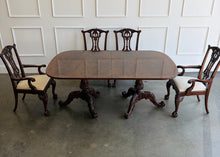 Load image into Gallery viewer, This vintage Drexel Heritage Nine Elms dining set showcases richly figured crotch mahogany veneer framed by contrasting banding. The expansive table rests on two ornately carved pedestal bases and includes three 22-inch leaves, extending it to an impressive 140 inches for large gatherings. Eight coordinating chairs—two armchairs and six side chairs. Good Bones Furniture
