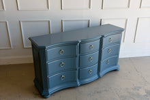 Load image into Gallery viewer, Vintage Ethan Allen dresser lacquered in Sherwin Williams Rain Cloud, the muted blue-gray color gives the piece a sophisticated, updated presence. The serpentine front adds movement across all nine drawers, while fluted corner details and a stepped base bring structure and depth. New brushed brass ring hardware. Good Bones Furniture