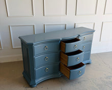 Load image into Gallery viewer, Vintage Ethan Allen dresser lacquered in Sherwin Williams Rain Cloud, the muted blue-gray color gives the piece a sophisticated, updated presence. The serpentine front adds movement across all nine drawers, while fluted corner details and a stepped base bring structure and depth. New brushed brass ring hardware. Good Bones Furniture