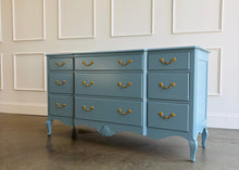 Load image into Gallery viewer, This vintage nine-drawer dresser by Ethan Allen combines generous storage with graceful traditional detailing. Professionally lacquered in a custom muted blue with soft gray undertones, the finish gives its classic silhouette a fresh, versatile look. Nine drawers provide abundant organized storage, while framed drawer fronts, a gently stepped top, curved apron, carved shell motif, and cabriole-style legs preserve its vintage character. Good Bones Furniture