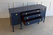 Load image into Gallery viewer, This vintage genuine mahogany sideboard combines generous storage with elegant Federal-inspired detailing. Professionally lacquered in Benjamin Moore In the Navy, its deep, classic navy finish highlights the fluted frieze, carved rosettes, decorative urn motifs, and slender tapered legs. New brass hardware. Good Bones Furniture