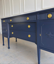 Load image into Gallery viewer, This vintage genuine mahogany sideboard combines generous storage with elegant Federal-inspired detailing. Professionally lacquered in Benjamin Moore In the Navy, its deep, classic navy finish highlights the fluted frieze, carved rosettes, decorative urn motifs, and slender tapered legs. New brass hardware. Good Bones Furniture