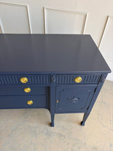 Load image into Gallery viewer, This vintage genuine mahogany sideboard combines generous storage with elegant Federal-inspired detailing. Professionally lacquered in Benjamin Moore In the Navy, its deep, classic navy finish highlights the fluted frieze, carved rosettes, decorative urn motifs, and slender tapered legs. New brass hardware. Good Bones Furniture