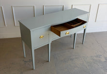 Load image into Gallery viewer, This vintage sideboard pairs a historic Hepplewhite-inspired silhouette with an unexpected modern color. Its gently bowed front, symmetrical layout, slender tapered legs, and balanced proportions reflect classic Federal design. Professionally lacquered in Sherwin-Williams Unusual Gray with new solid brass oval bail pulls with ornate neoclassical backplates. Good Bones Furniture