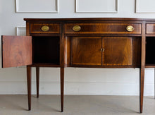 Load image into Gallery viewer, Vintage Hickory Chair sideboard showcasing classic Federal-inspired styling with beautifully banded mahogany veneers, graceful serpentine lines, and tapered legs. The thoughtfully designed layout includes three drawers above three cabinet compartments, offering versatile storage for dining essentials, serving pieces, or barware. Rich mahogany grain, satin brass hardware, and refined inlay details. Good Bones Furniture